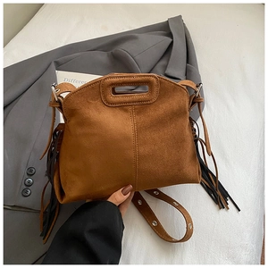 Detail of bohemian brown suede bag featuring long fringe tassels and metal grommet strap