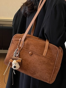 Minimalist brown suede bowling bag with a cute plush dog pendant and shoulder straps