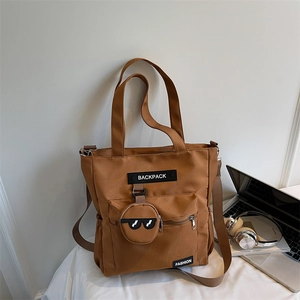 Détail du sac fourre-tout marron avec porte-monnaie rond, ordinateur et casque sur bureau