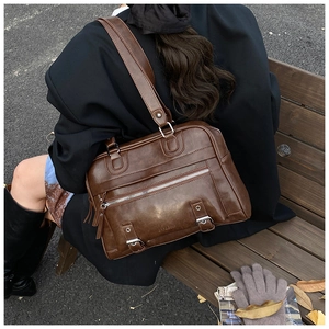 Detail of a vintage dark brown tote bag on a wooden bench showing leather texture