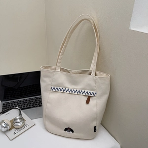 Détail du sac fourre-tout en toile crème avec broderie de chien et ruban rayé décoratif