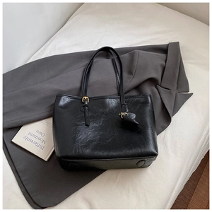 Detail of black faux leather tote bag showing textured PU material and gold hardware