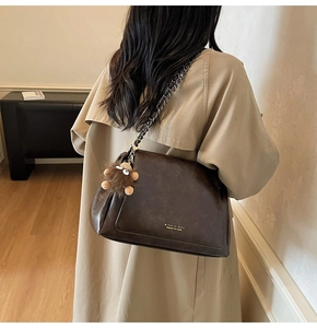 Detailed back view of a brown vintage leather tote bag with a plush bear charm