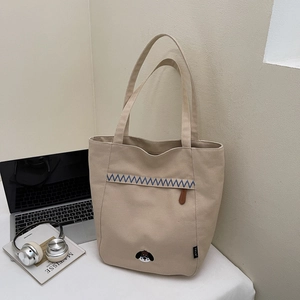 Détail du sac cabas en toile beige avec broderie chien et surpiqûre bleue en zigzag