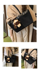 Detail of black canvas and leather tote bag featuring a cute brown plush bear charm