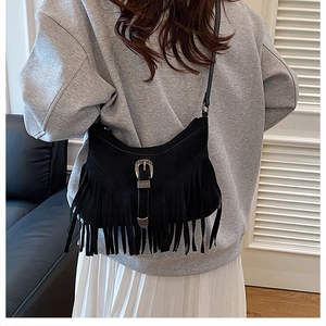 Close-up of black matte suede shoulder bag featuring long fringe and vintage metal buckle