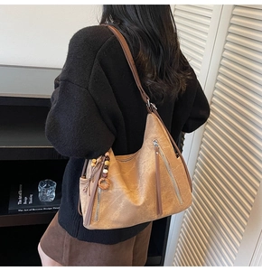 Brown vintage hobo tote bag with fringe tassels shown on a model in a cozy home setting