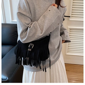 Close-up of black suede fringe bag with retro silver western buckle and tassel detail