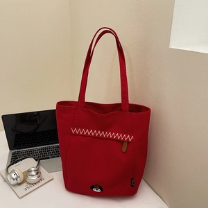 Détail du sac cabas en toile rouge avec broderie chien et coutures zigzag beige