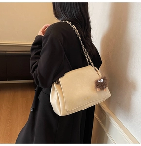 Detail view of beige matte leather flap bag with gold chain strap and plush monster charm