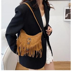 Close-up of bohemian brown suede shoulder bag featuring long fringe and vintage buckle