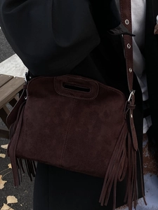 Retro brown suede fringe crossbody bag with wide shoulder strap in autumn street setting