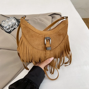 Detail of a brown suede moon bag featuring retro metal buckle and long decorative tassels