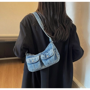 Detail of light blue denim motorcycle bag with silver buttons on wide shoulder strap