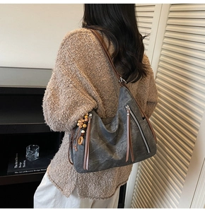 Detail view of deep gray vintage tote bag with brown leather straps and beaded tassel