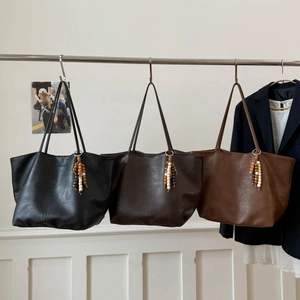 Three large leather tote bags in black, dark brown, and tan with beaded tassels