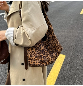 Detail of a large leopard print tote bag with suede texture and brown leather straps