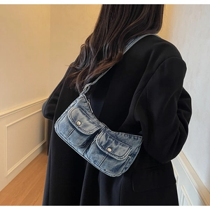 Detailed close-up of retro washed blue denim shoulder bag with dual utility pockets