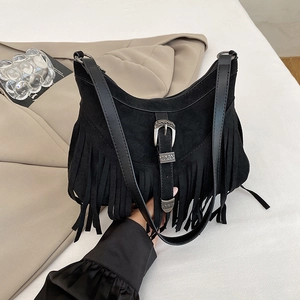 Detail of vintage black suede tassel shoulder bag featuring an ornate metal buckle