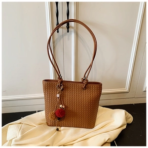 Detailed view of brown woven tote bag texture with colorful bead and pompom charm