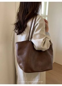 Deep brown retro tote bag shown on model wearing beige coat in minimalist setting