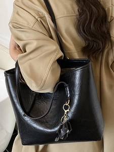 Large black vintage tote bag with dual handles and gold hardware shown on a model