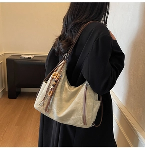 Detail of vintage canvas hobo bag with wooden bead pendant and tassel on the leather strap
