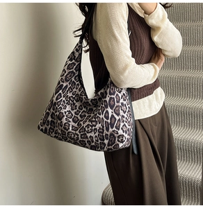 Detailed close-up of a large leopard print tote bag featuring a black shoulder strap