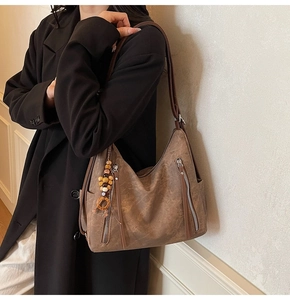 Detail of vintage brown hobo bag with multiple zippers and ethnic beaded tassel pendant