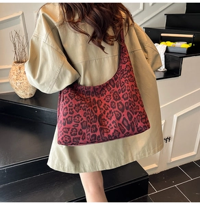 Detail of red leopard print suede hobo bag with wide strap on a khaki trench coat