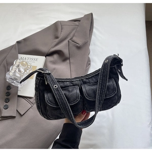 Detail of dark gray vintage denim shoulder bag with utility pockets and metal eyelets