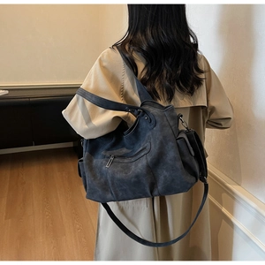 Dettaglio della grande borsa tote vintage grigio scuro indossata con un trench kaki alla moda