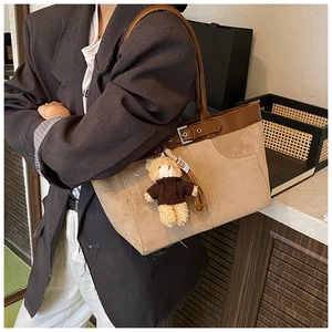 Detail of khaki suede tote bag with brown leather trim and cute bear charm accessory