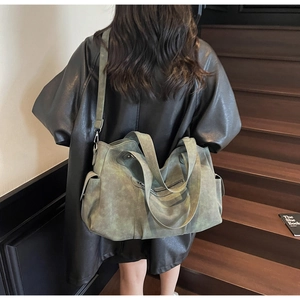 Borsa tote vintage verde salvia indossata da una modella su una scala di legno