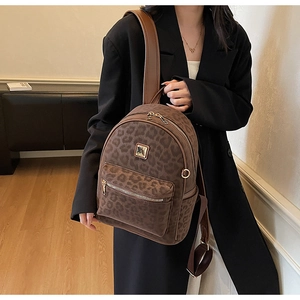 Detail view of the leopard print backpack showing the golden metal logo and PU texture