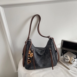 Detail of retro grey hobo shoulder bag with brown leather strap and wooden bead tassel