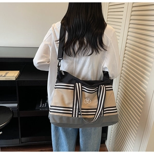 Détail du grand sac cabas en toile avec bandoulière rayée porté par un modèle