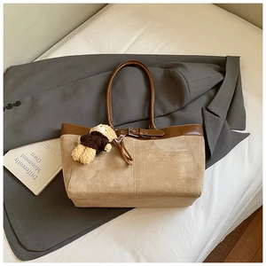 Detail of beige suede tote bag with brown leather trim and a cute bear bag charm accessory