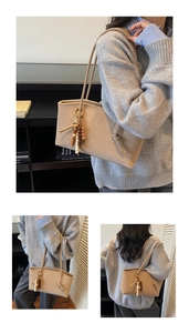 Detail of beige tote bag with a bohemian bead charm and premium leather texture