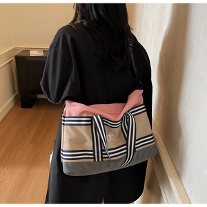Détail d'un sac cabas en toile multicolore avec bandoulière porté par un modèle