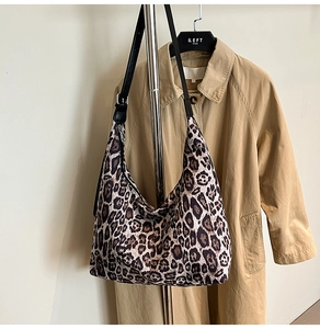 Detail of leopard print tote bag featuring black leather strap and adjustable metal buckle