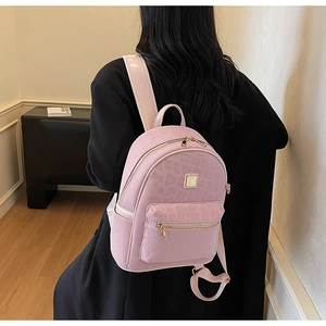 Rear view of a pink leopard print backpack worn by a model in a minimal indoor setting