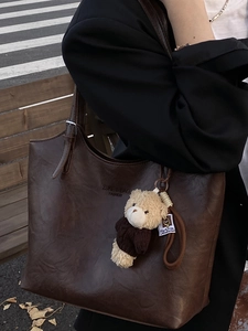 Deep brown oversized tote bag with vintage leather texture and cute plush bear charm