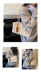 Close-up of beige leather tote bag with wooden bead charm and embossed logo detail