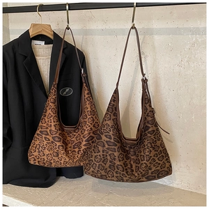 Detail view of large leopard print hobo bags with brown straps hanging on a rack