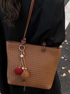 Vintage brown woven leather tote bag with elegant tassel charm and slim shoulder straps