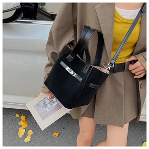 Detail of black suede bucket bag with leather strap and silver metal twist lock