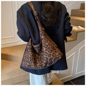 Detail of leopard print tote bag with brown leather strap worn over the shoulder