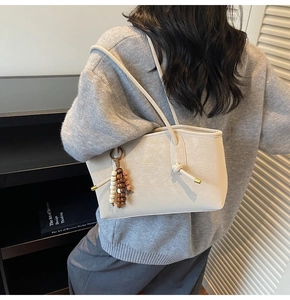 Close-up of beige leather tote bag featuring colorful wooden beads and soft texture