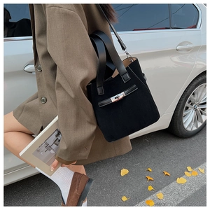 Detail of black suede bucket bag with buckle and silver hardware in autumn setting